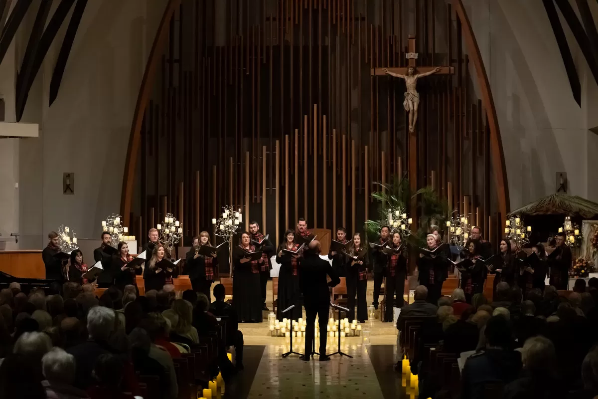 Pacific Chorale performing Carols by Candlelight surrounded by warm candlelight.